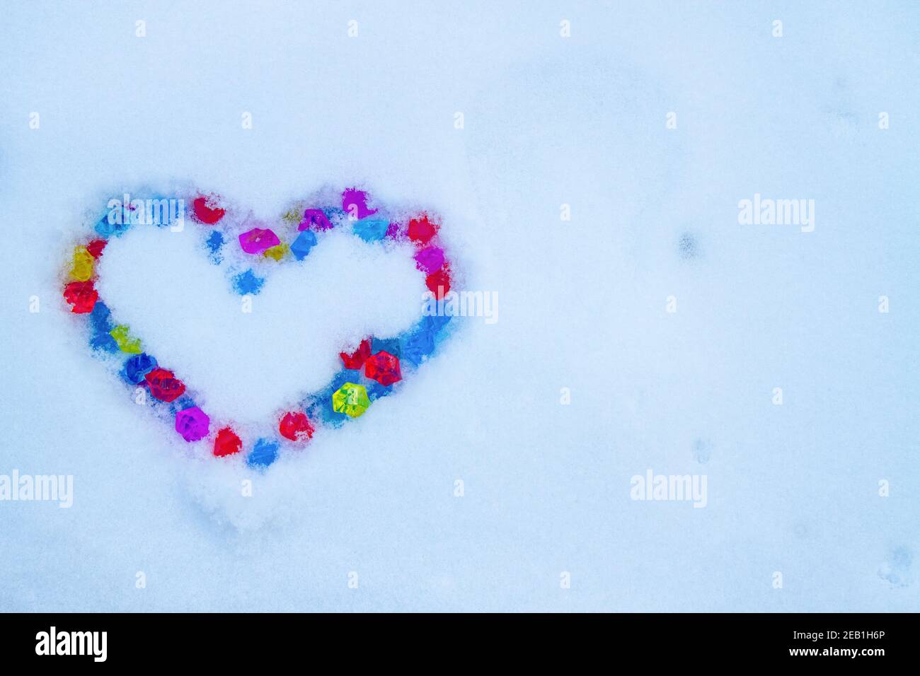 Cuore fatto di cristalli multicolore sulla neve Foto Stock