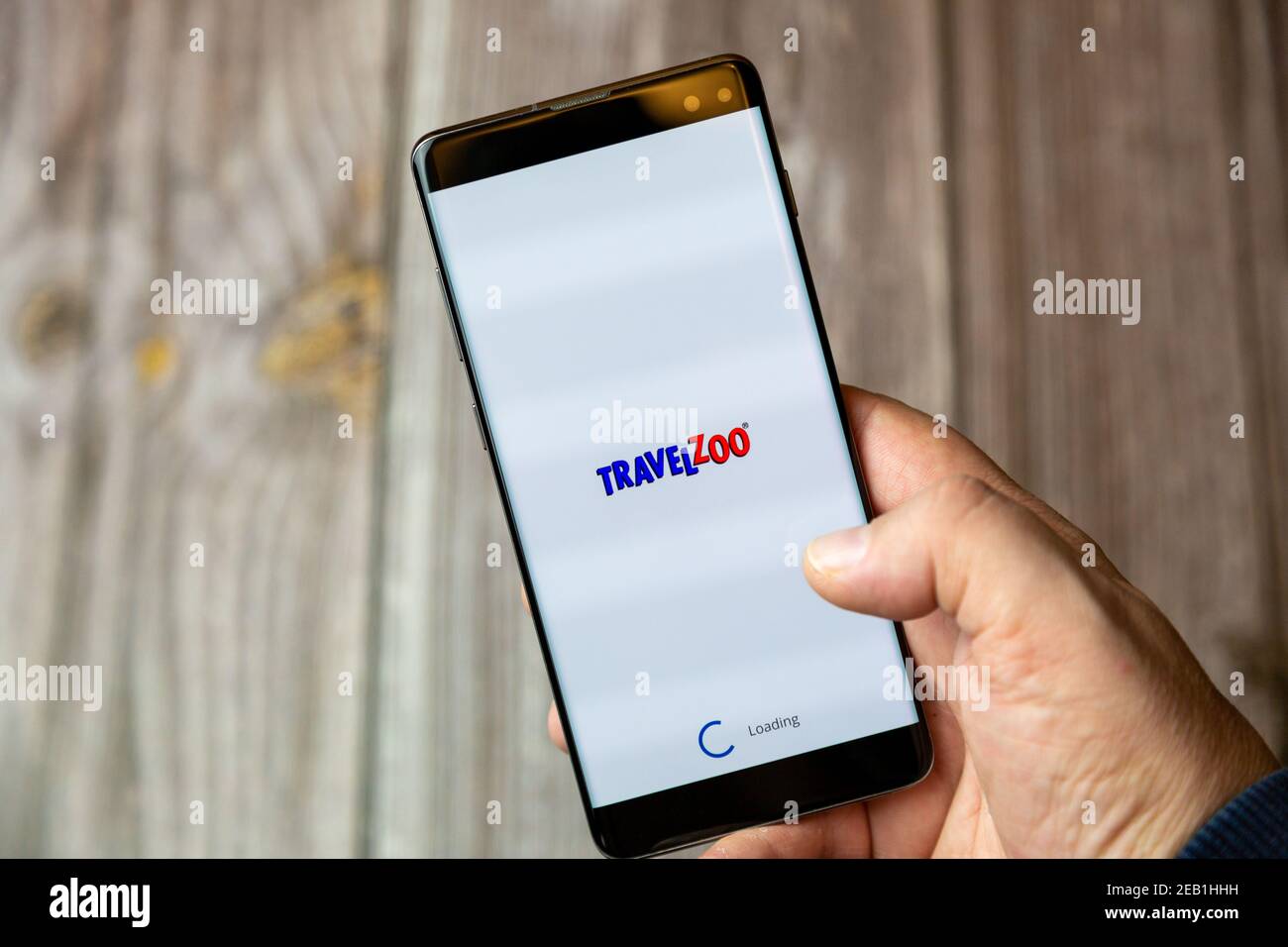 Un telefono cellulare o un telefono cellulare tenuto da un Mano con l'app Travelzoo aperta sullo schermo Foto Stock