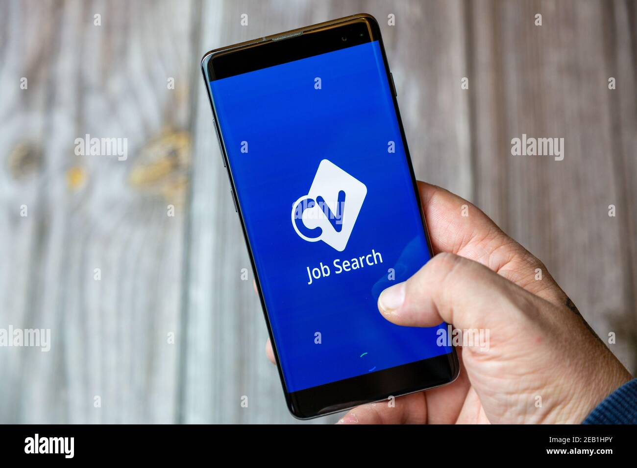 Un telefono cellulare o un telefono cellulare tenuto da un Insieme all'app CV Library Jobsearch aperta sullo schermo Foto Stock