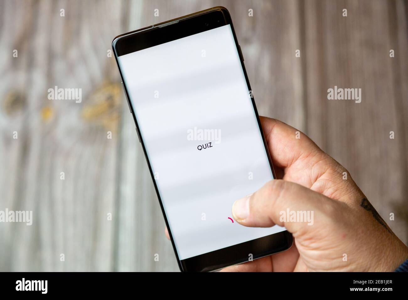 Un telefono cellulare o un telefono cellulare tenuto da un Mano con l'app Quiz aperta sullo schermo Foto Stock