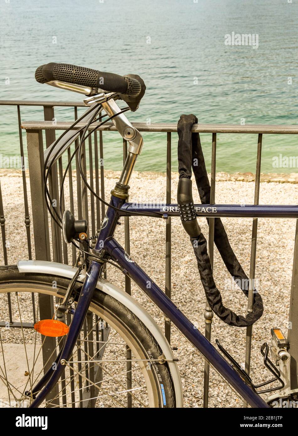 GARDA, LAGO DI GARDA, ITALIA - SETTEMBRE 2018: Primo piano panoramica della serratura di sicurezza e del cavo che fissa una bicicletta a ringhiere metalliche sul lungomare di Garda Foto Stock