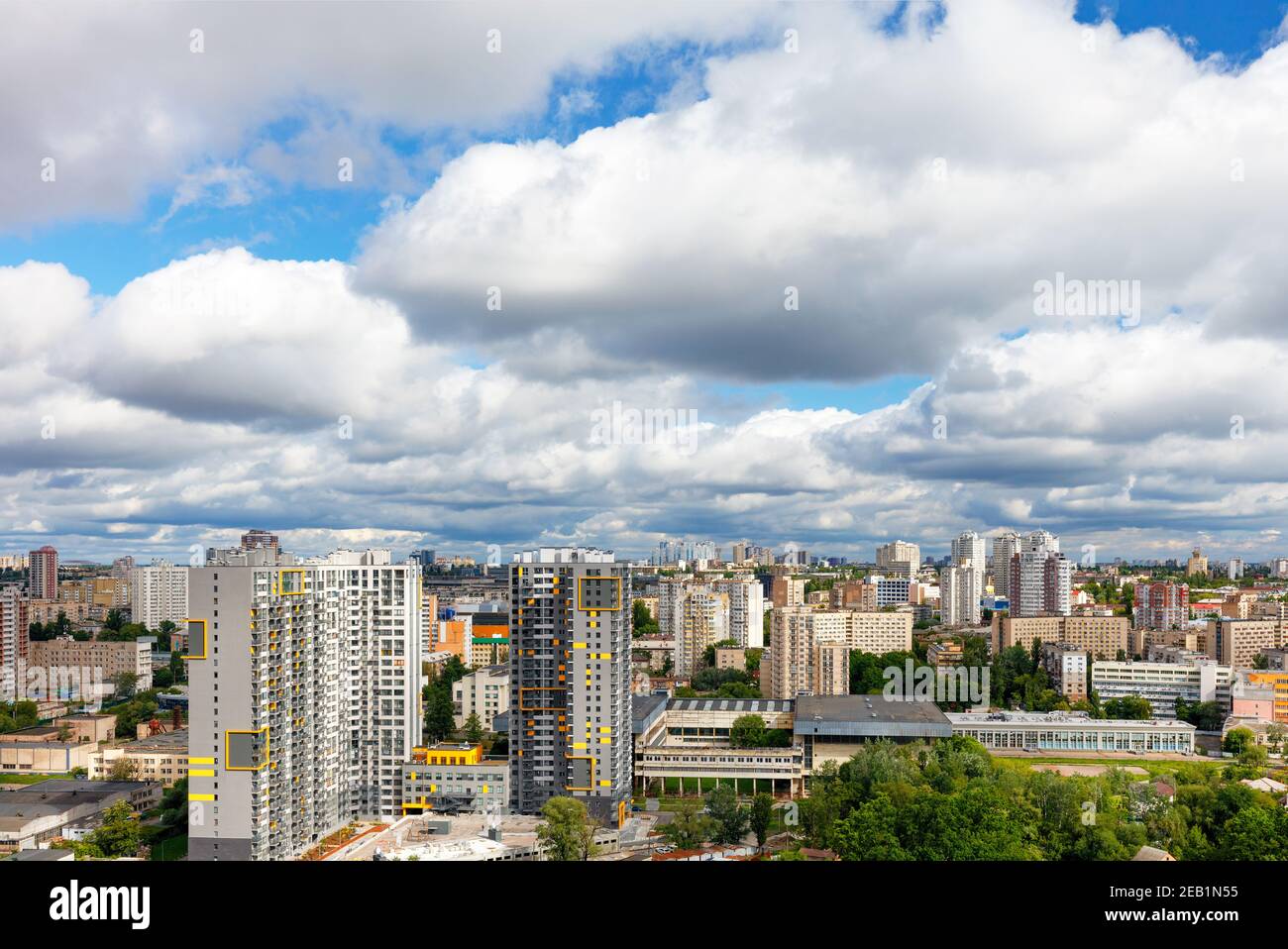 Un paesaggio urbano con architettura alta e bassa sotto un bel cielo drammatico con dense nuvole spesse. Foto Stock