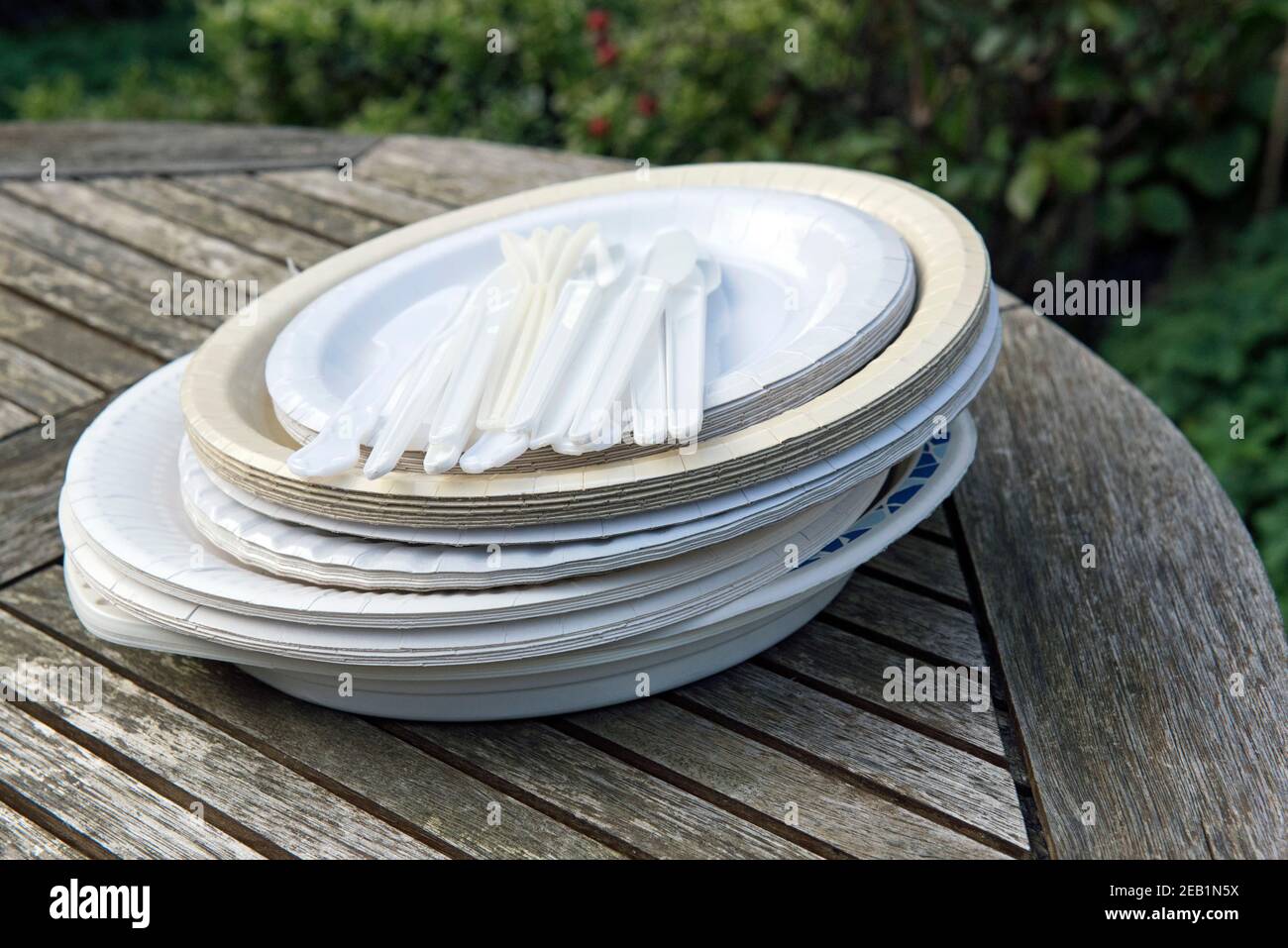 Piatti di carta assortiti con posate in plastica monouso sul tavolo da giardino Foto Stock