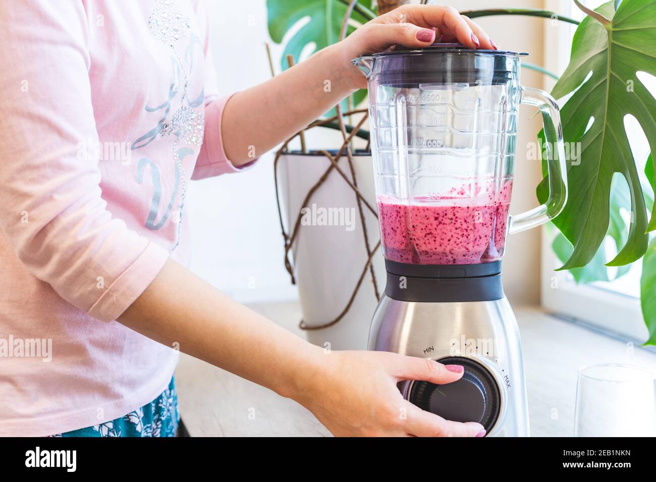 Una donna mescola il frullato di bacche in un frullatore. Il concetto di uno stile di vita sano. Foto Stock