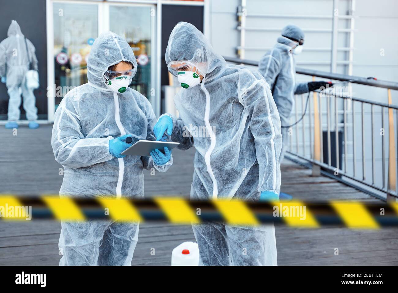 Operatori sanitari che indossano tute nocciole che lavorano insieme durante un focolaio in città Foto Stock