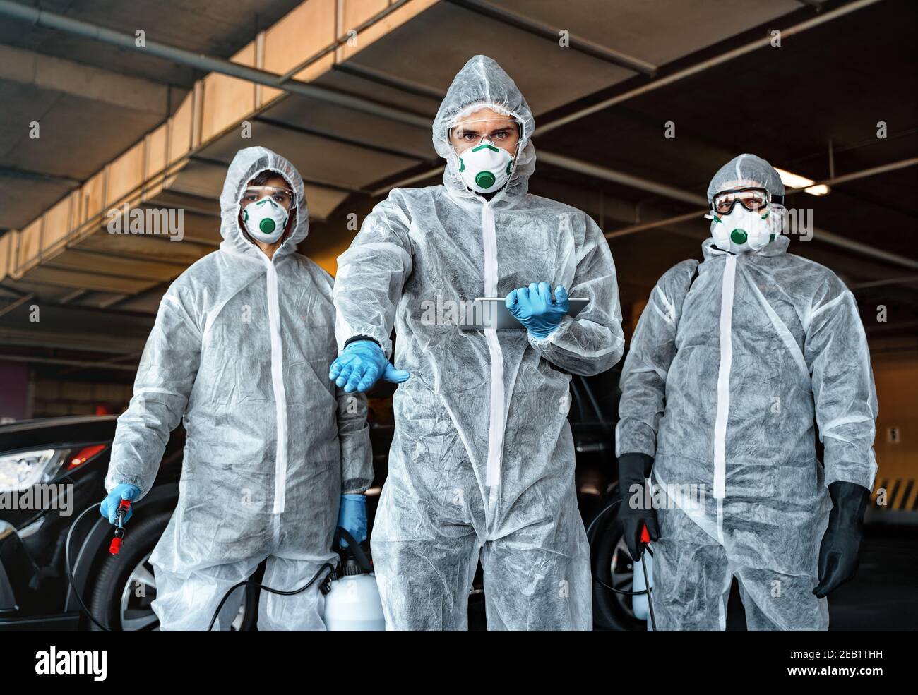 L'operatore sanitario consiglia di non lasciare la zona di quarantena. Team di operatori sanitari che indossano tute nocciole che lavorano insieme per controllare un focolaio Foto Stock