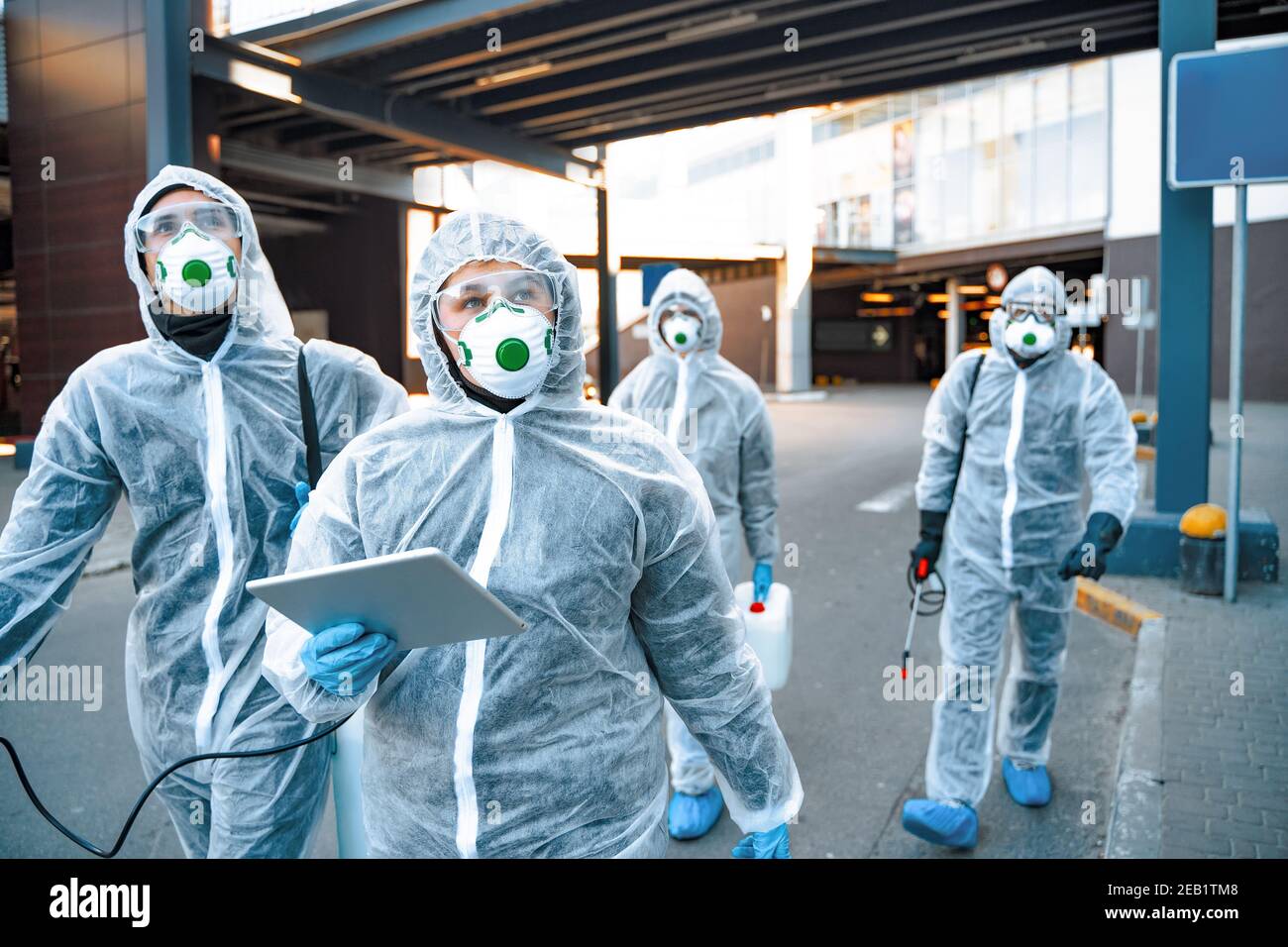 Operatori sanitari che indossano tute nocciole che lavorano insieme durante un focolaio in città Foto Stock