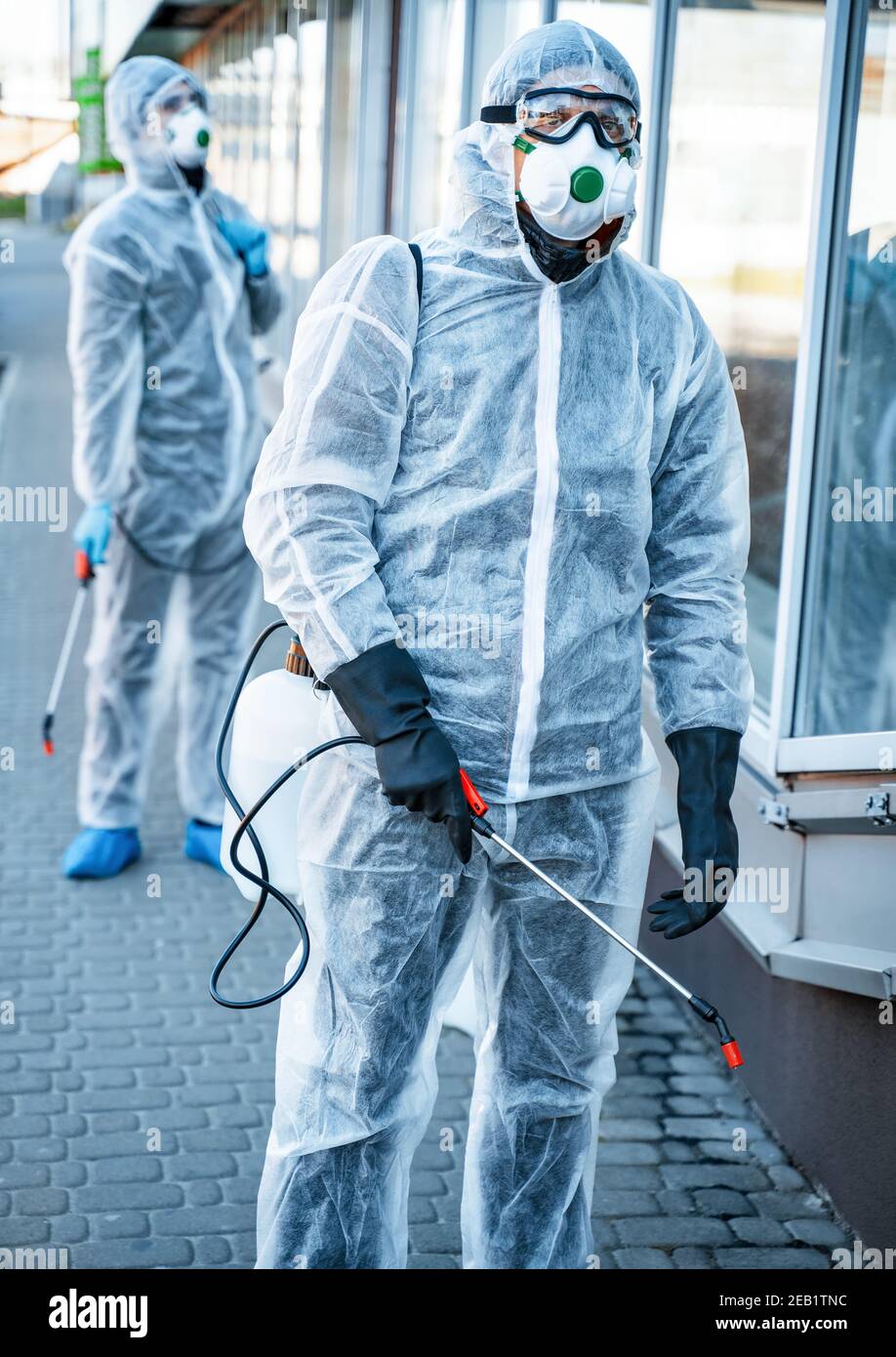 Decontaminazione. Operatori sanitari che indossano abiti di nocciolo che lavorano insieme durante un focolaio in città Foto Stock