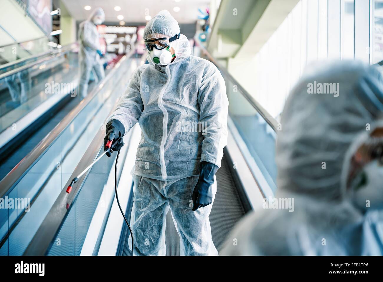Operaio disinfettante in tuta protettiva che effettua la disinfezione nel centro commerciale, per controllare un focolaio di virus nella città Foto Stock