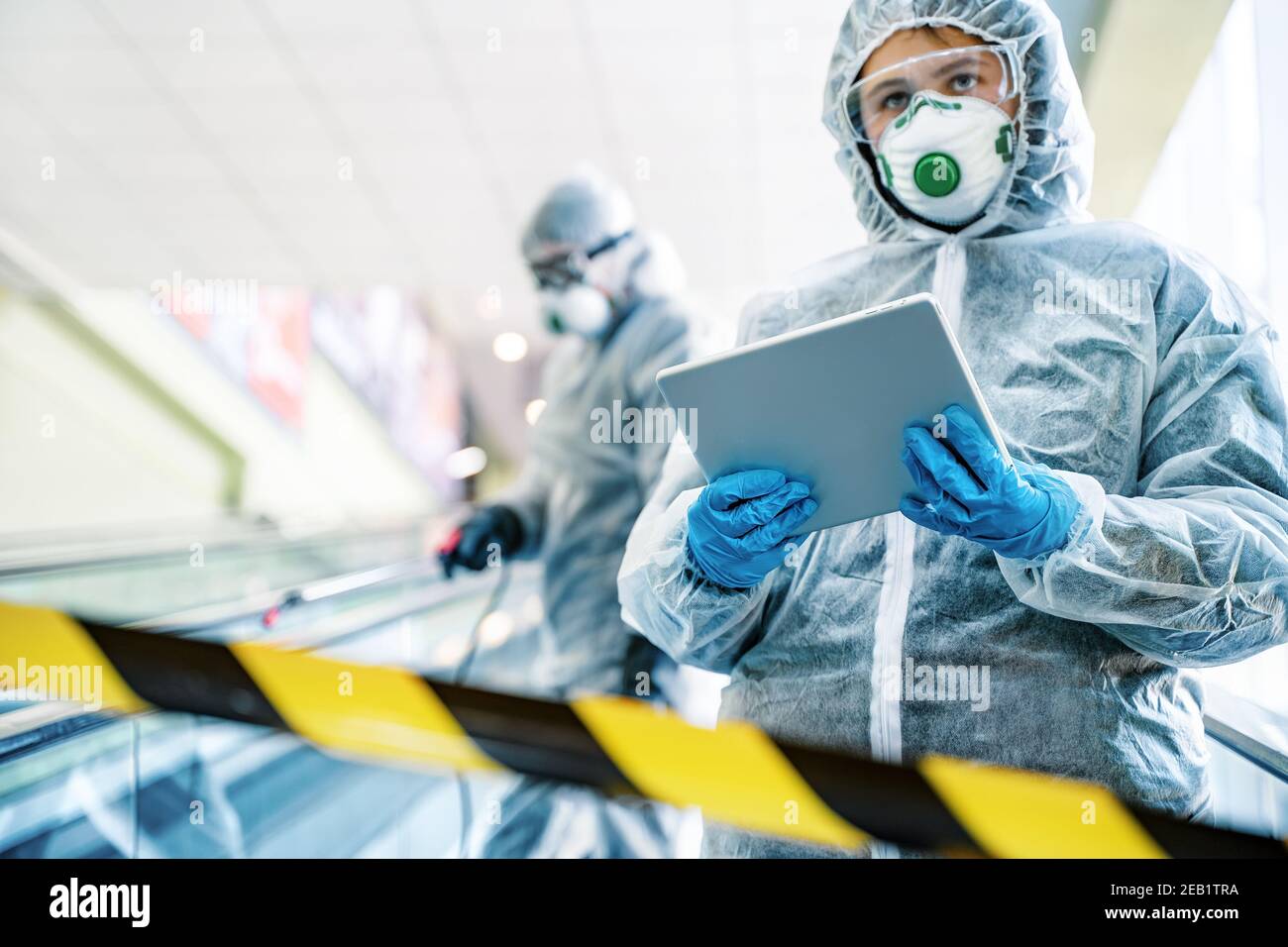 Operatori sanitari che indossano abiti di nocciolo che lavorano insieme nel centro commerciale, per controllare un focolaio di virus in città Foto Stock