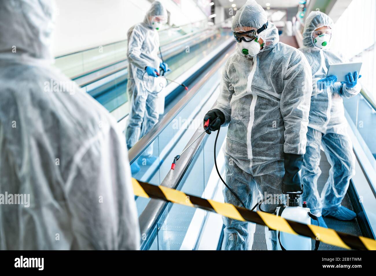 Operatori disinfettanti in indossare abiti di nocciolo fare disinfezione nel centro commerciale, per controllare un focolaio di virus in città Foto Stock