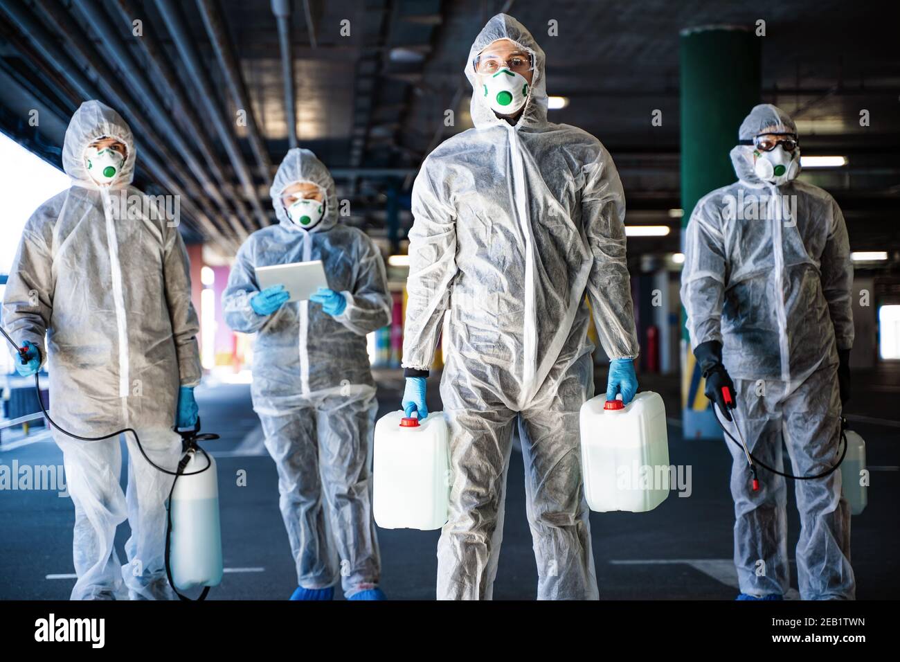 Un team di operatori sanitari che indossano tute nocciole che lavorano insieme controllare un focolaio Foto Stock