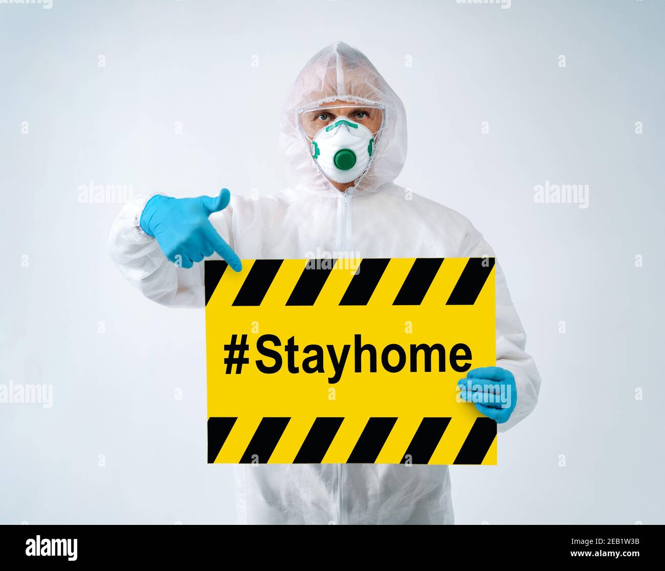 Operatore sanitario in tuta protettiva e maschera medica punti su carta con testo ''stayhome' Foto Stock
