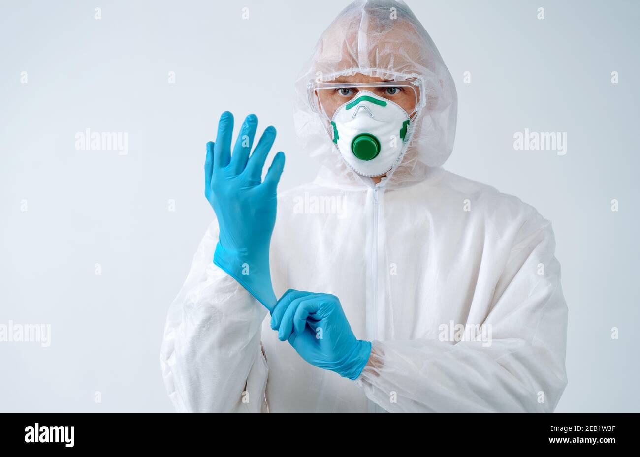 Operatore sanitario in tuta protettiva e maschera medica indossa i guanti. Concetto di assistenza sanitaria. Foto Stock