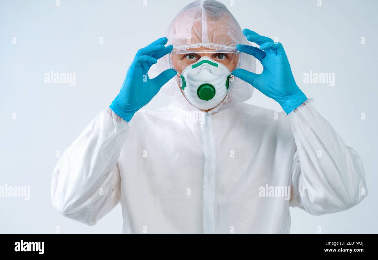 Operatore sanitario in tuta protettiva e maschera medica mette su occhiali. Concetto di assistenza sanitaria. Foto Stock