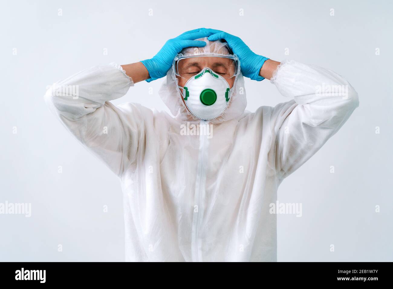 Stanco lavoratore in tuta protettiva e maschera medica su bianco sfondo Foto Stock