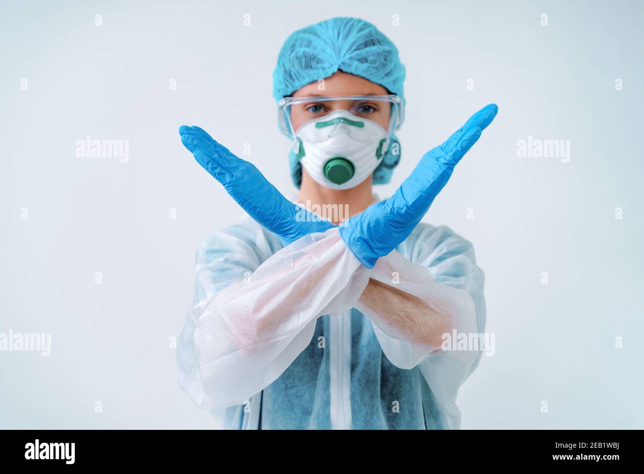 Operatore sanitario in tuta protettiva e maschera medica che mostra gesto di arresto, per controllare un focolaio di virus Foto Stock