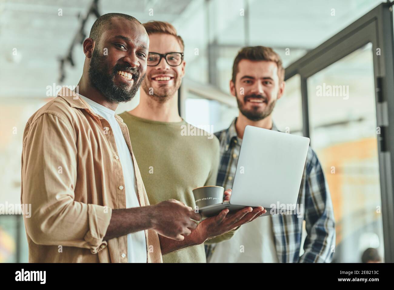 Tre giovani uomini di lavoro multirazziali che posano per la macchina fotografica Foto Stock