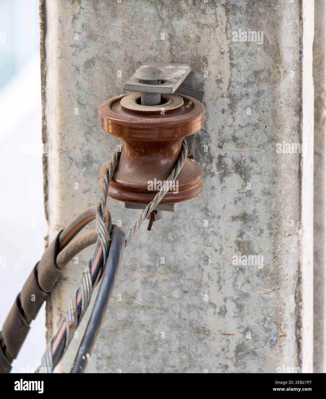 Un cavo elettrico appeso a un rullo montato su un palo di cemento, primo piano. Foto Stock
