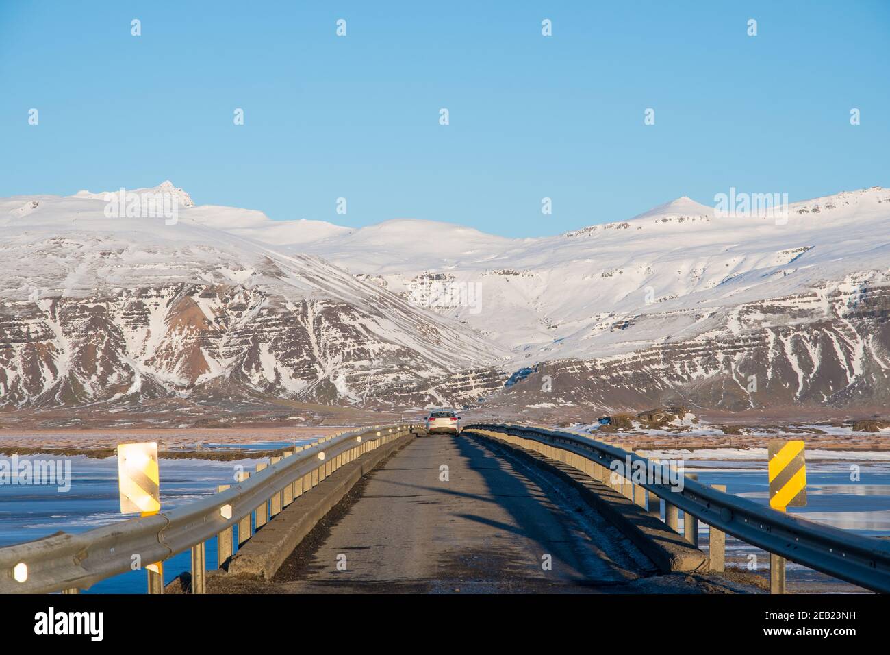 auto che attraversa un ponte a corsia singola su un fiume La campagna islandese in una soleggiata giornata invernale Foto Stock