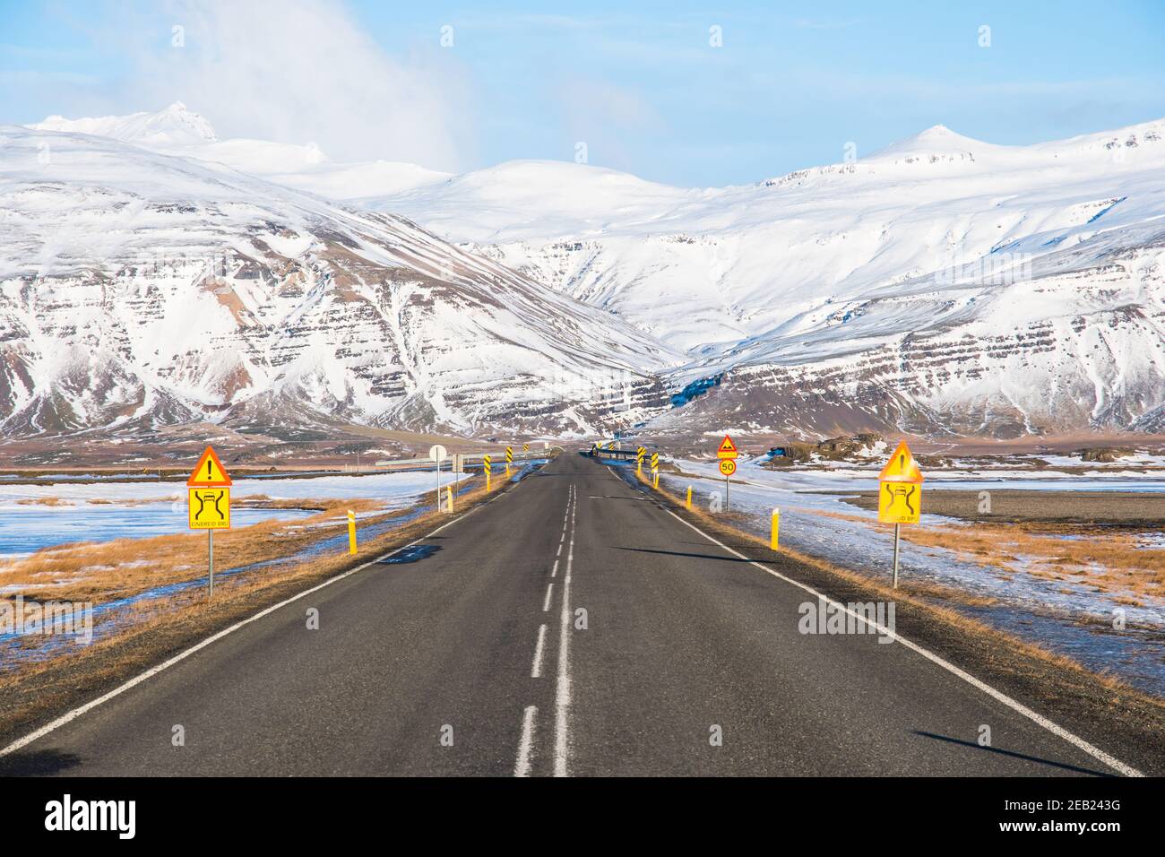 Strada sulla campagna islandese che si avvicina a un ponte a corsia singola Foto Stock
