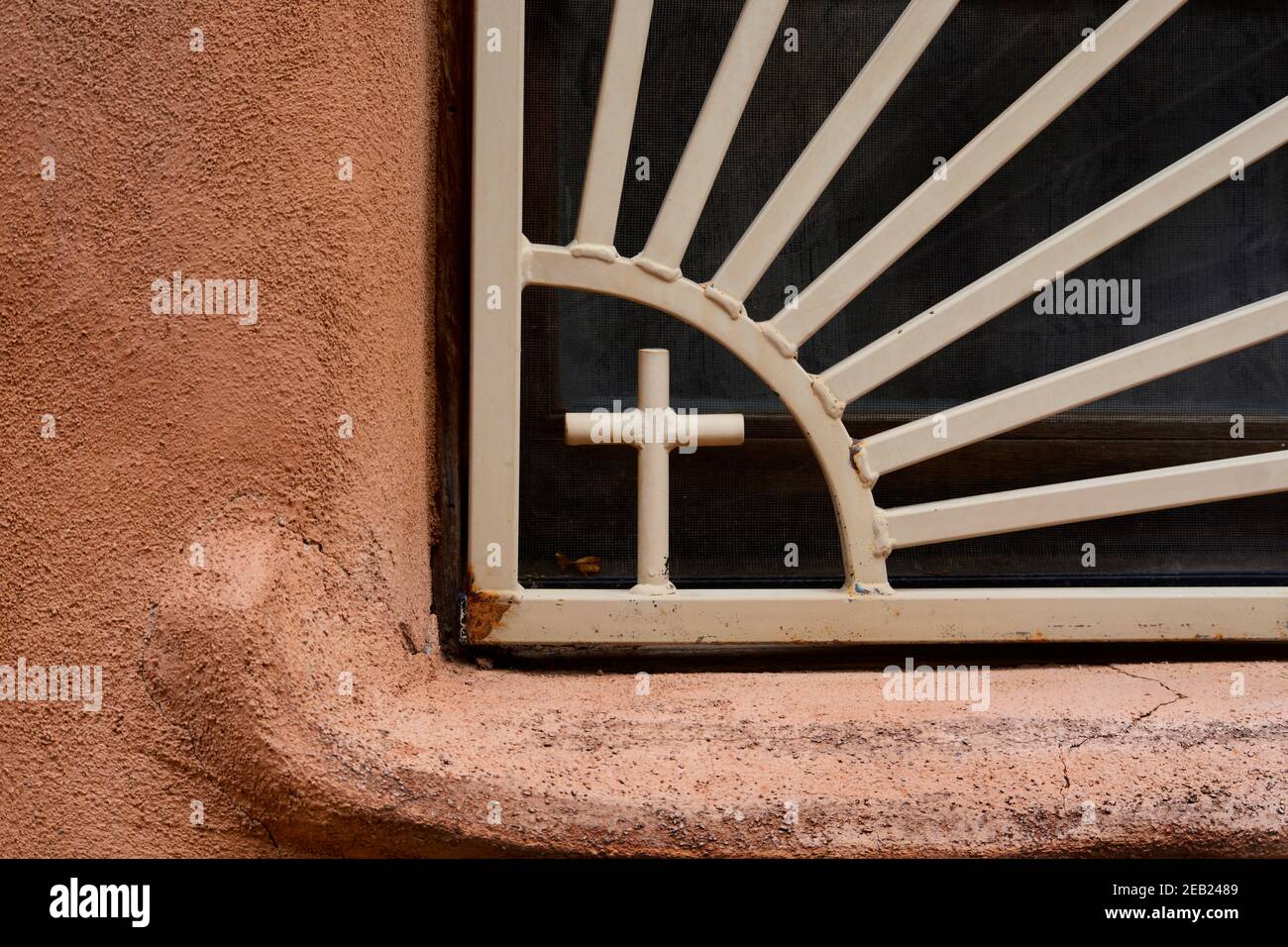 Barre di sicurezza delle finestre con un crocifisso o disegno a croce in una piccola cappella cattolica storica a Chimayo, New Mexico. Foto Stock
