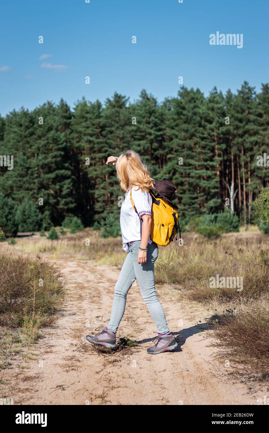 Donna escursionista con zaino camminare sul sentiero in natura. Donne escursioni turistiche all'aperto durante la giornata solo d'estate Foto Stock