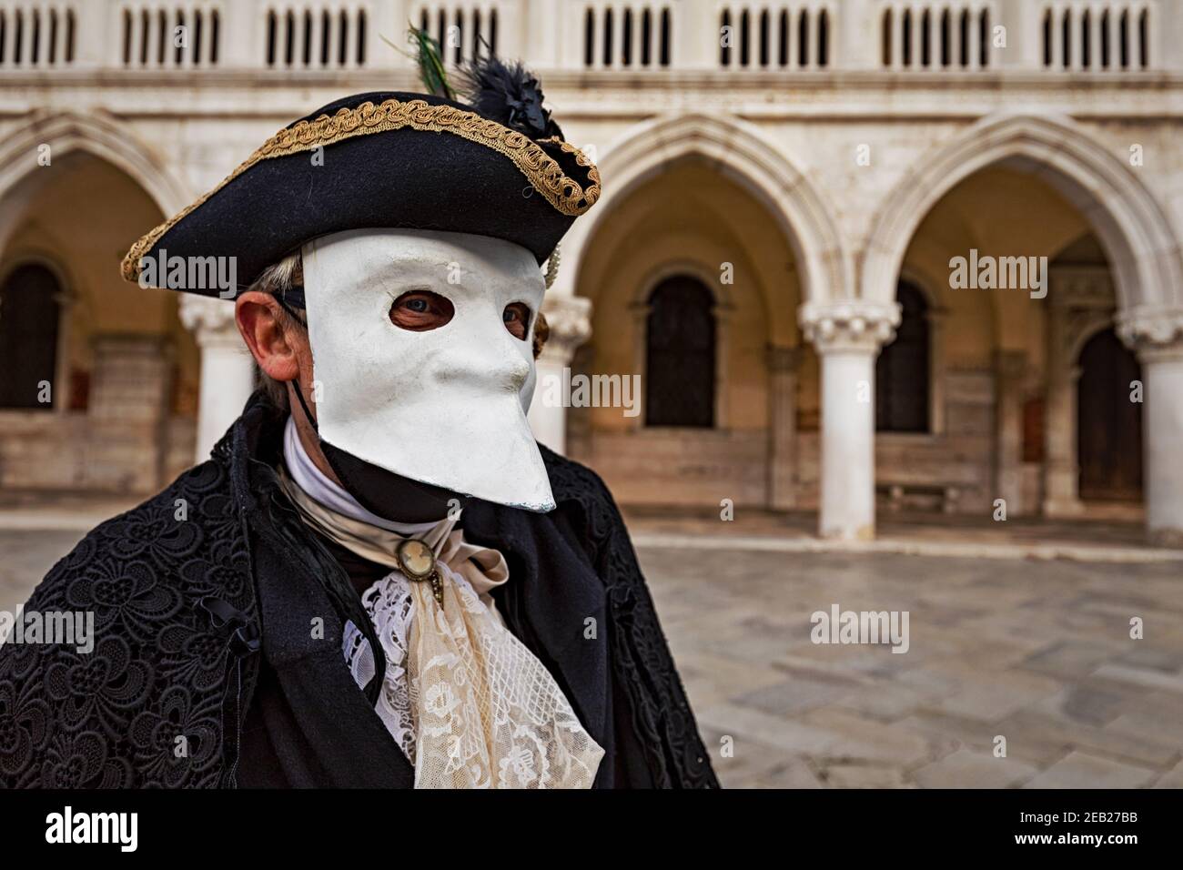 Tradizionale costume Bauta con mantello, cappello tricornato con piume e maschera bianca di lava. Periodo del Carnevale di Venezia durante la pandemia febbraio 2021. Foto Stock