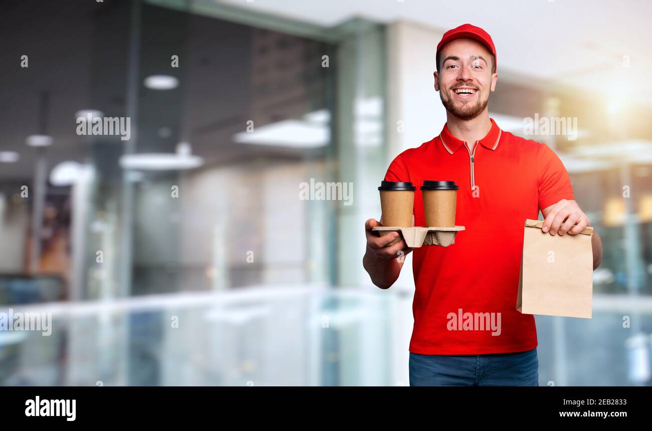 Il corriere è felice di consegnare caffè caldo e cibo a. casa Foto Stock