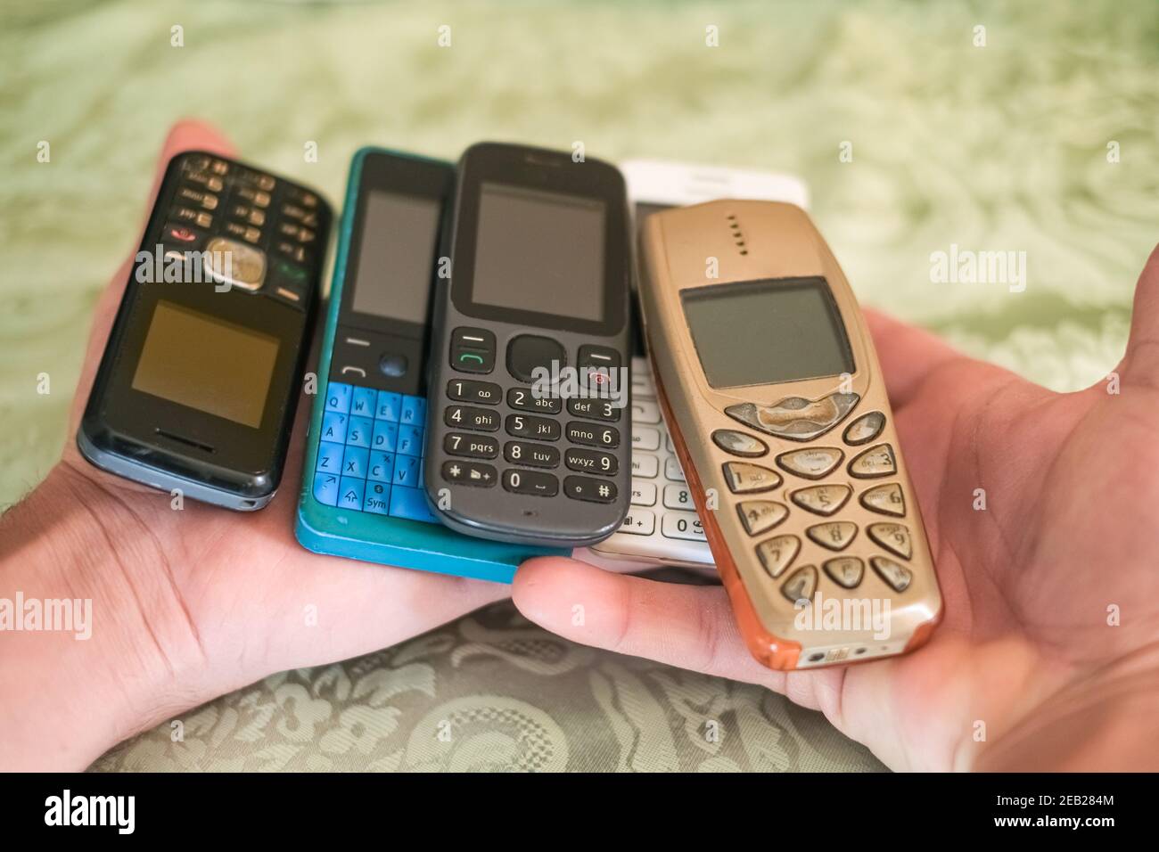 Mano dell'uomo mentre tiene il mucchio dei telefoni mobili di vecchia generazione, tecnologia concetto Foto Stock