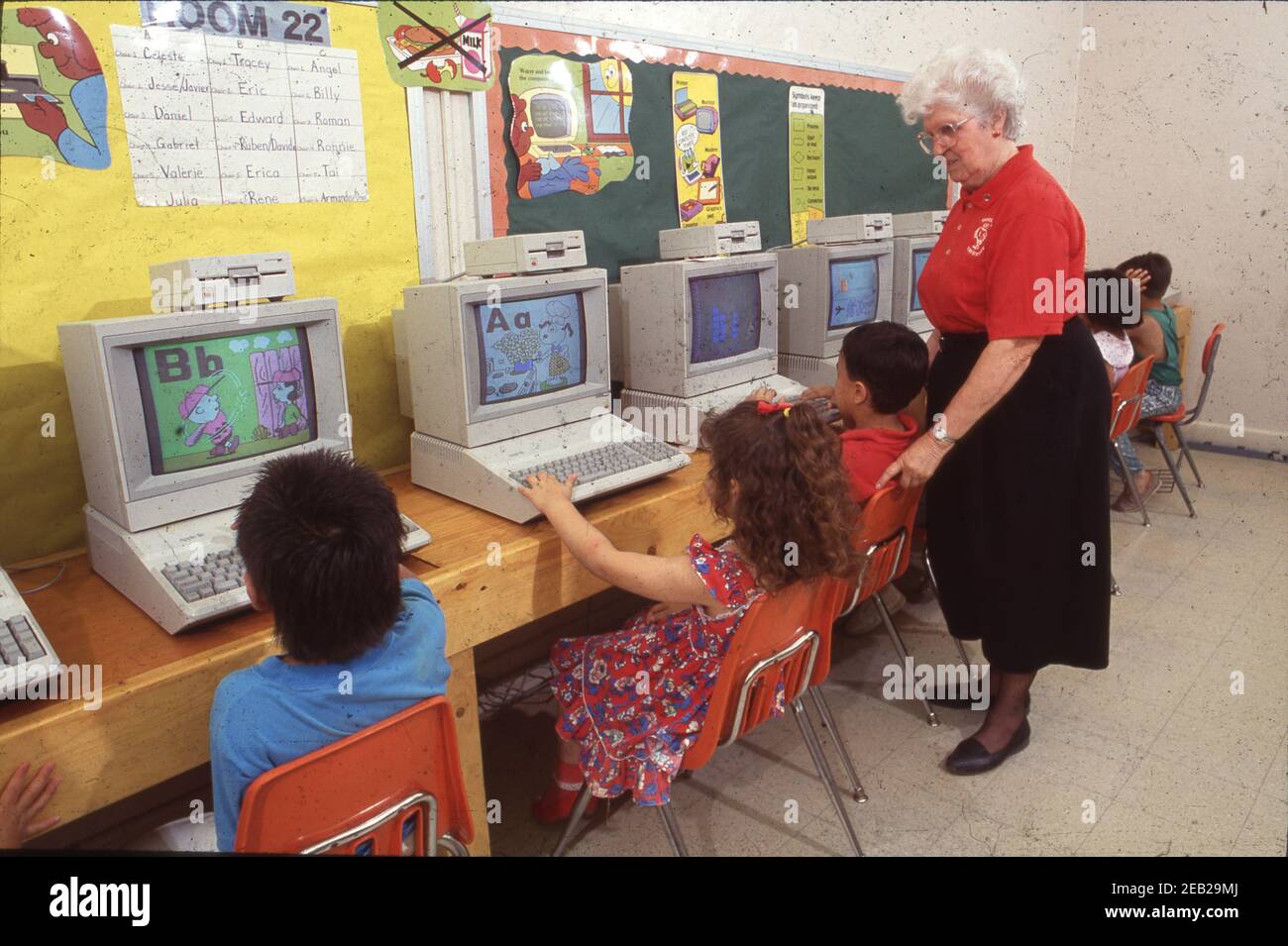 San Antonio, Texas USA: Insegnante con capelli grigi supervisiona gli studenti dell'asilo ispanico in un laboratorio di informatica presso la scuola elementare. Versione del modello EV-08-11. ©1991 Bob Daemmrich BAD3384D Foto Stock