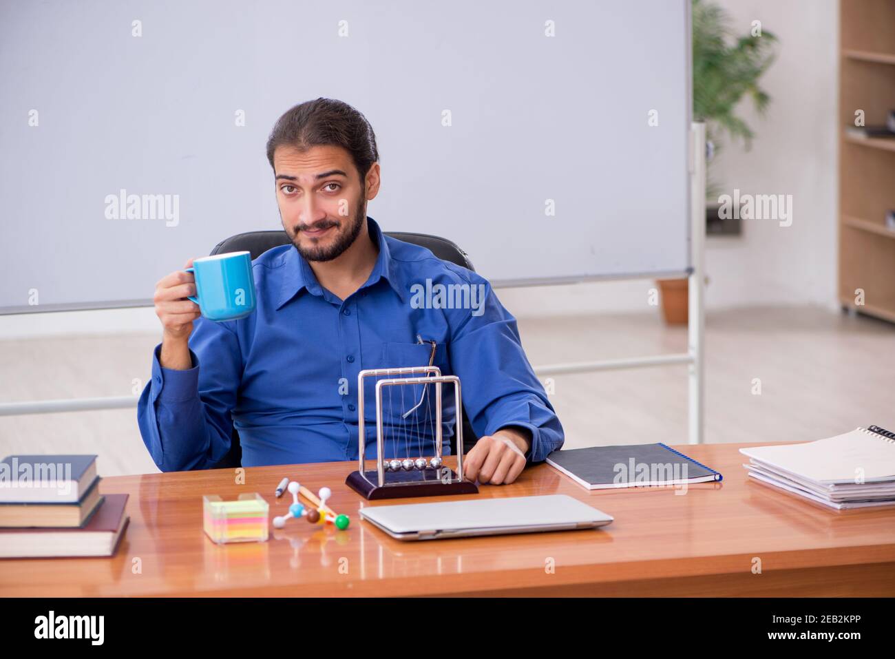 Fisico di un giovane insegnante seduto in classe Foto Stock