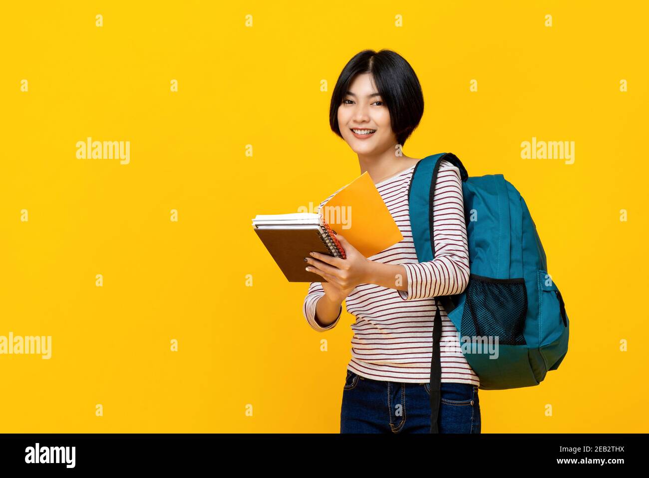 Giovane donna asiatica sorridente studente universitario con zaino tenere libri studio girato per il concetto di istruzione Foto Stock