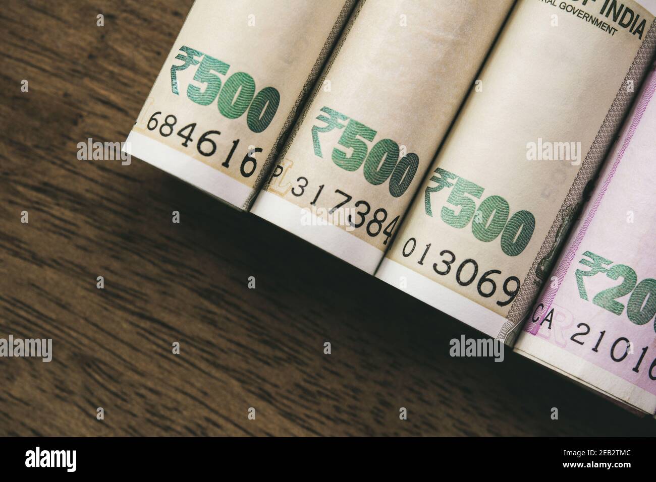 Rotoli di banconote in rupie indiane su sfondo di legno per concetto finanziario e di investimento Foto Stock