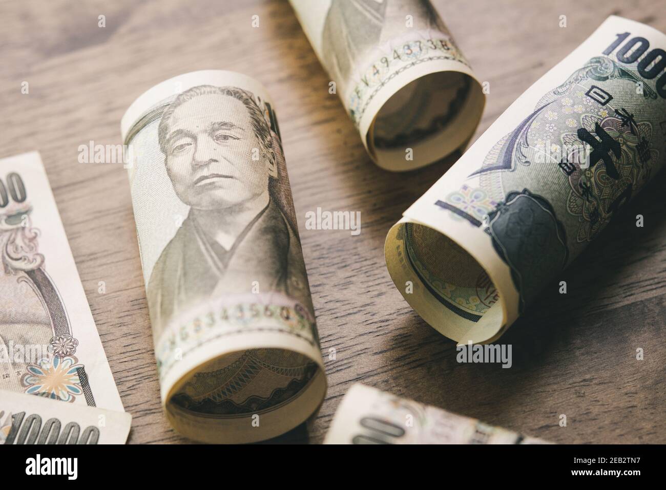 Rotoli di banconote in yen giapponesi su tavola di legno per concetti finanziari e di investimento Foto Stock