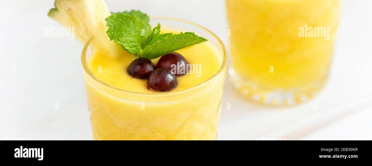 Primo piano di rinfrescante bevanda estiva all'ananas sullo sfondo del tavolo in marmo, formato banner Foto Stock