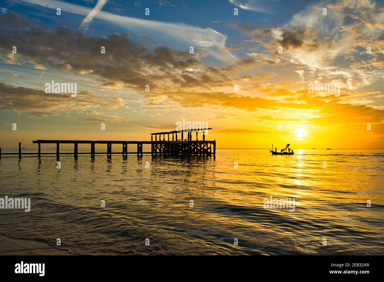 Vecchio ponte e barca da pesca Silhouette durante il cielo dorato e le nuvole sono molto belle a Pranburi, Prachuap Khiri Khan, Thailandia Foto Stock