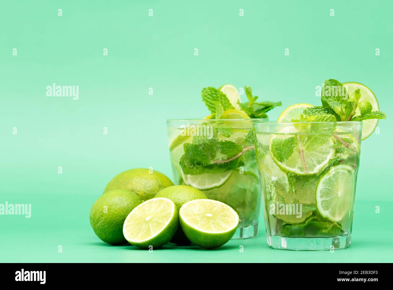 Rinfrescanti cocktail Mojito nei bicchieri a fette fresche lime e foglie di menta piperita su sfondo verde Foto Stock