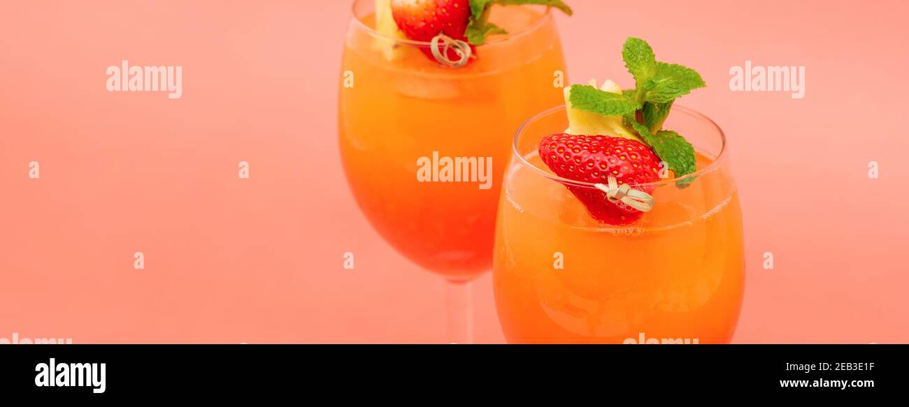 Cocktail colorati e rinfrescanti all'alba con fragola e arancio nei bicchieri su sfondo corallo rosa banner Foto Stock