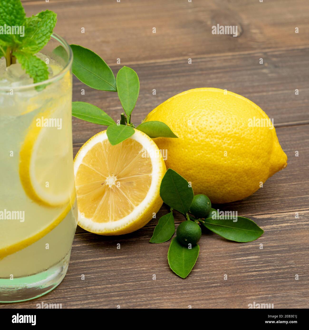 Bevanda rinfrescante al succo di limonata nel bicchiere con i limoni tavolo di legno sfondo Foto Stock