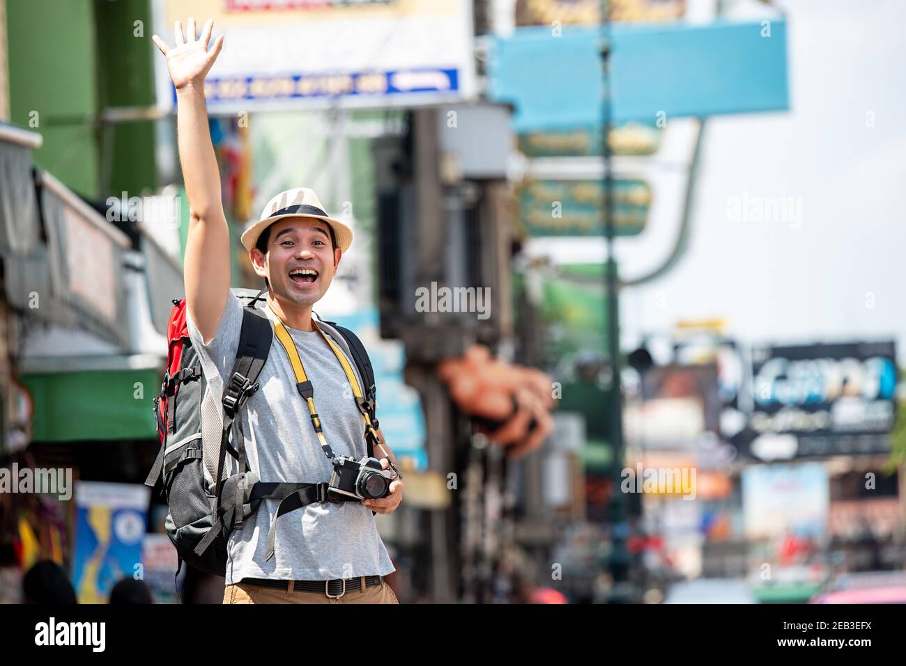 Eccitata persona turistica asiatica alzando la mano per salutare qualcuno In Khaosan strada Bangkok Thailandia Foto Stock