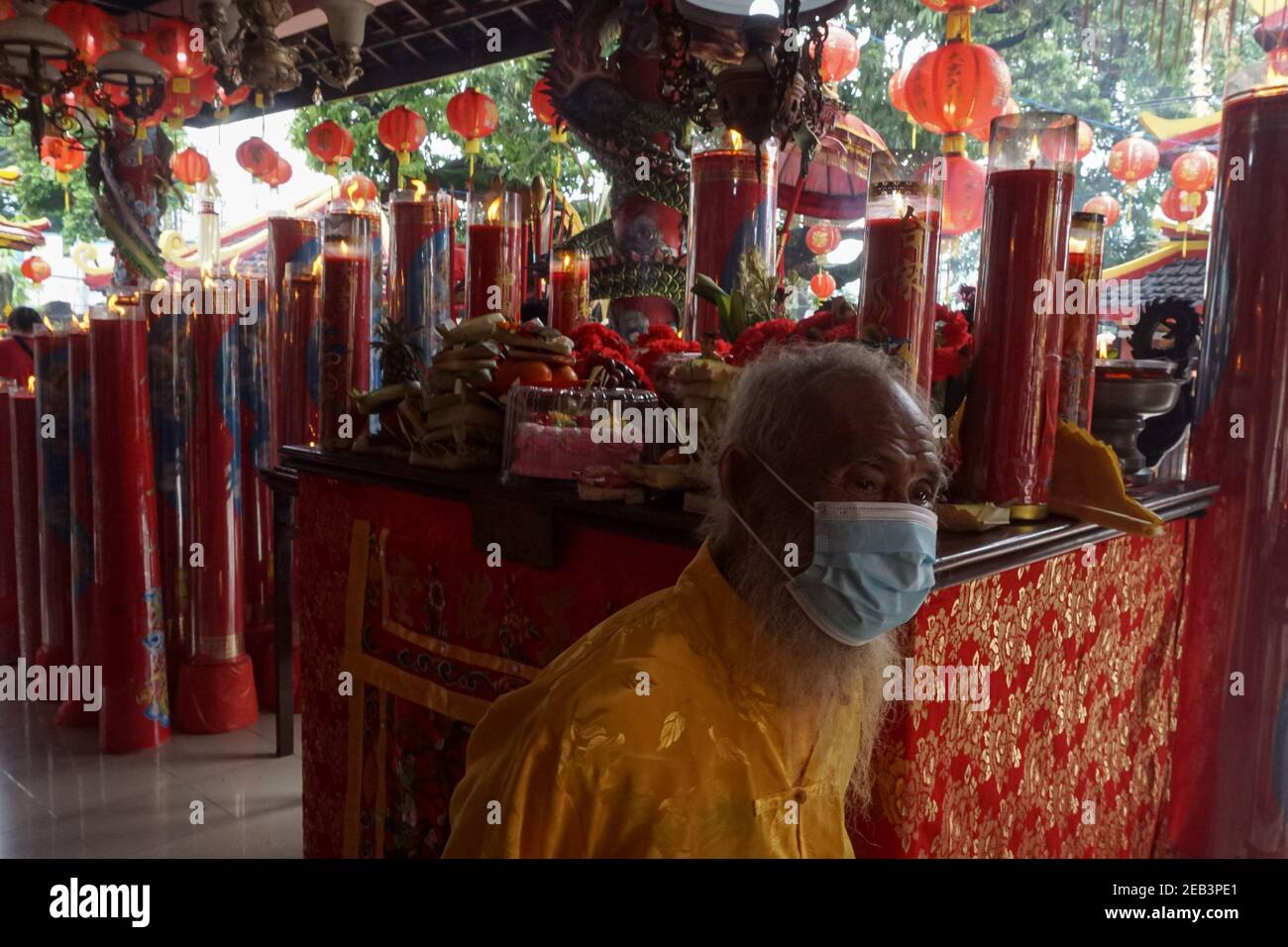 Badung, Bali, Indonesia. 12 Feb 2021. Un uomo che indossa la maschera cammina tra le candele giganti. Il popolo cinese e i discendenti di Bali eseguono una preghiera per celebrare il Capodanno lunare 2021 nel tempio Dharmayana di Kuta. Il nuovo anno come segno dell'anno dell'Ox inizia nel calendario cinese. Credit: Dicky Bisinglasi/ZUMA Wire/Alamy Live News Foto Stock