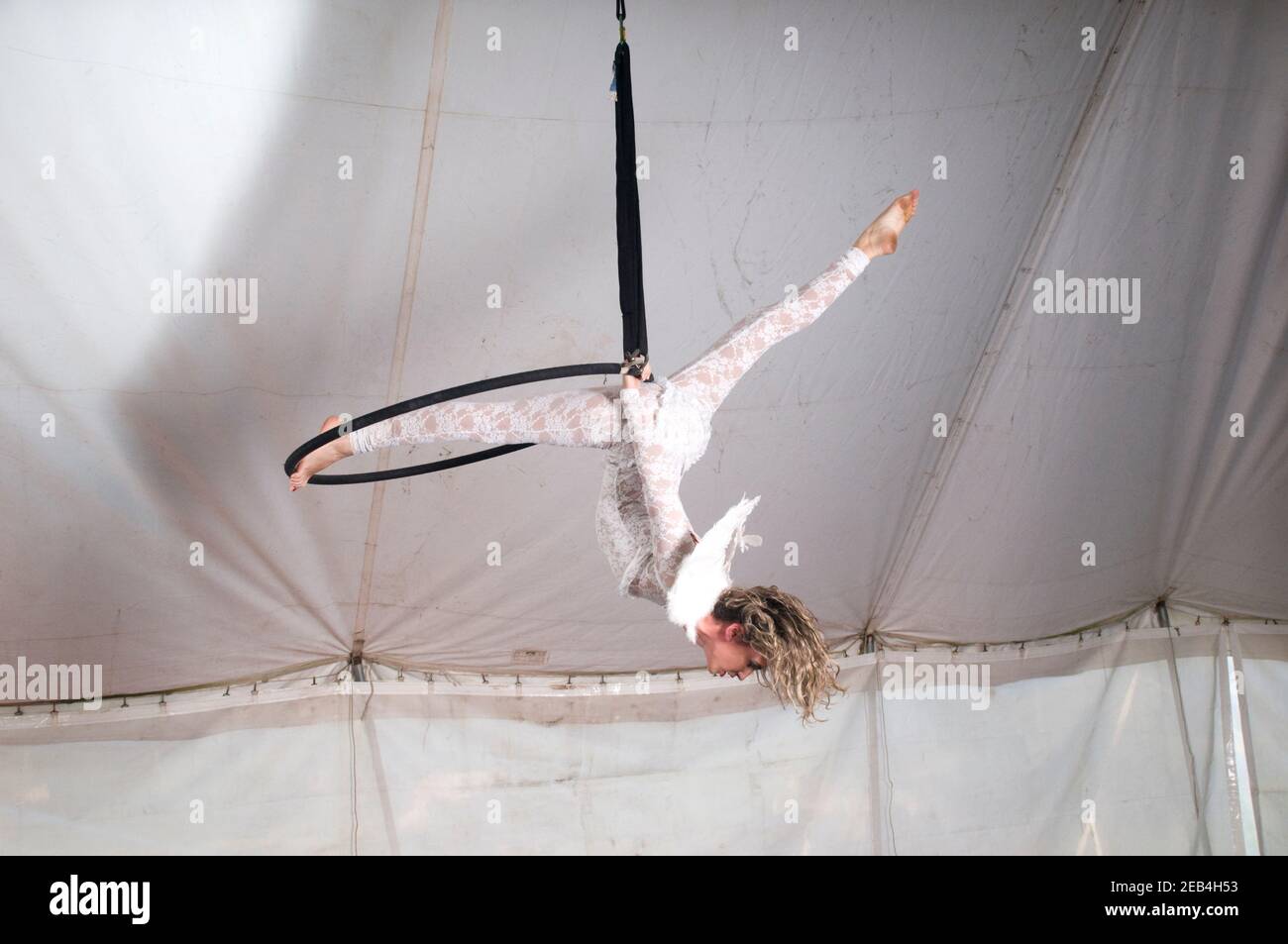La donna Aerialist acrobat con ali ad angolo si esibisce in aria su un cerchio in una tenda circense Foto Stock