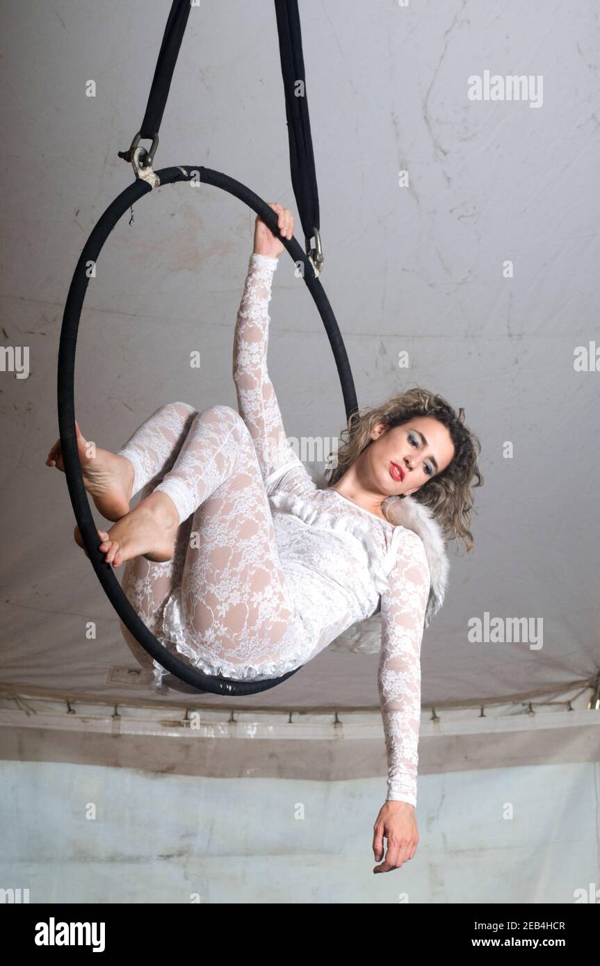 La donna Aerialist acrobat con ali ad angolo si esibisce in aria su un cerchio in una tenda circense Foto Stock