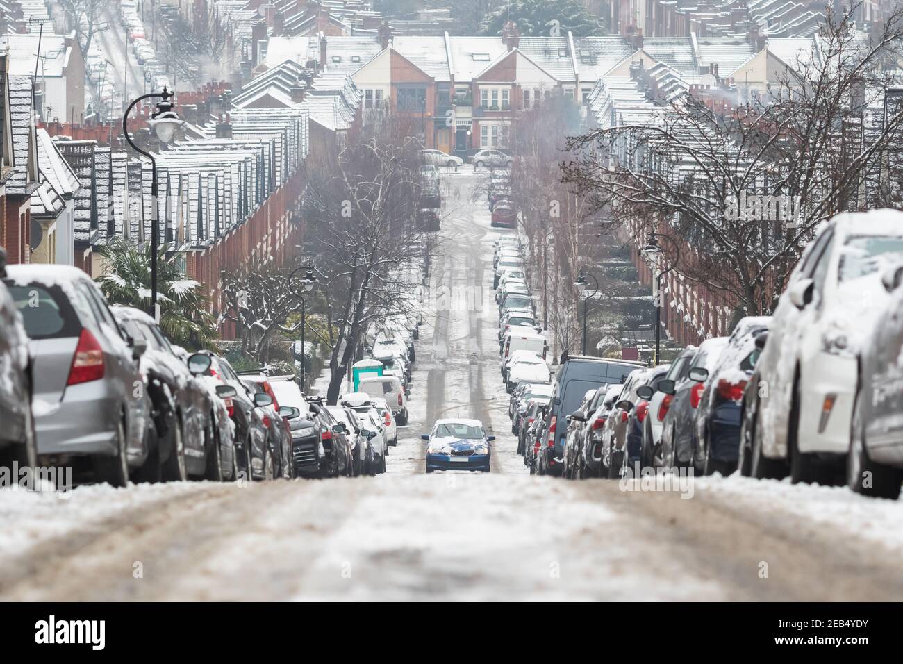 Un'auto che guida in salita su una strada coperta di neve a Crouch End, a nord di Londra, condizioni di guida avverse Foto Stock