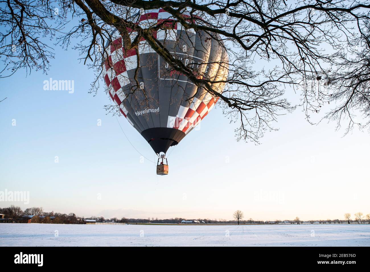 Heissluftballon über den verschneiten Wiesen bei Willich in den Nachmittagstorden. Foto Stock