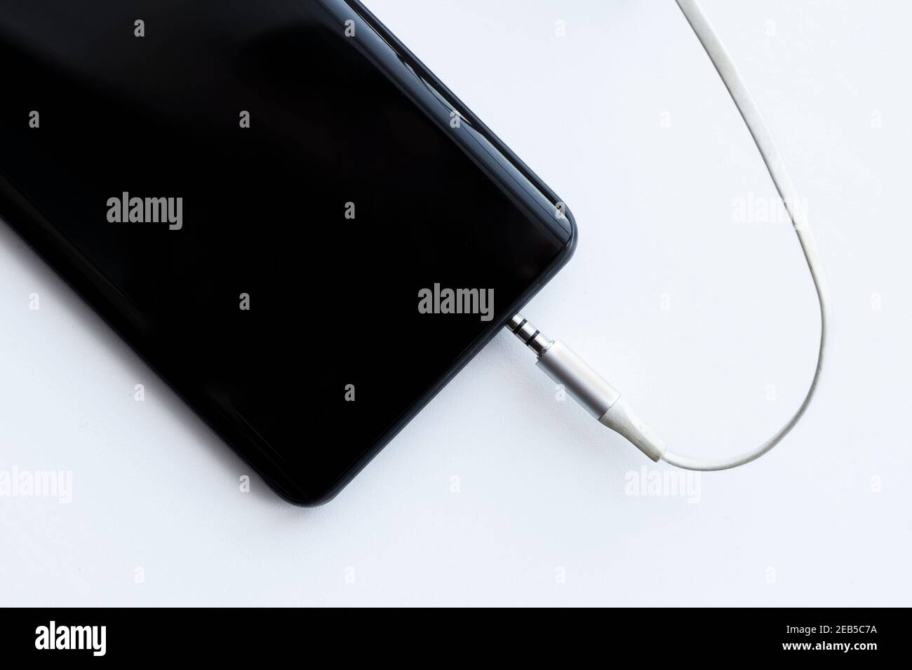 jack per cavo audio per smartphone mobile da 3,5 mm e foro di ingresso su uno sfondo bianco Foto Stock