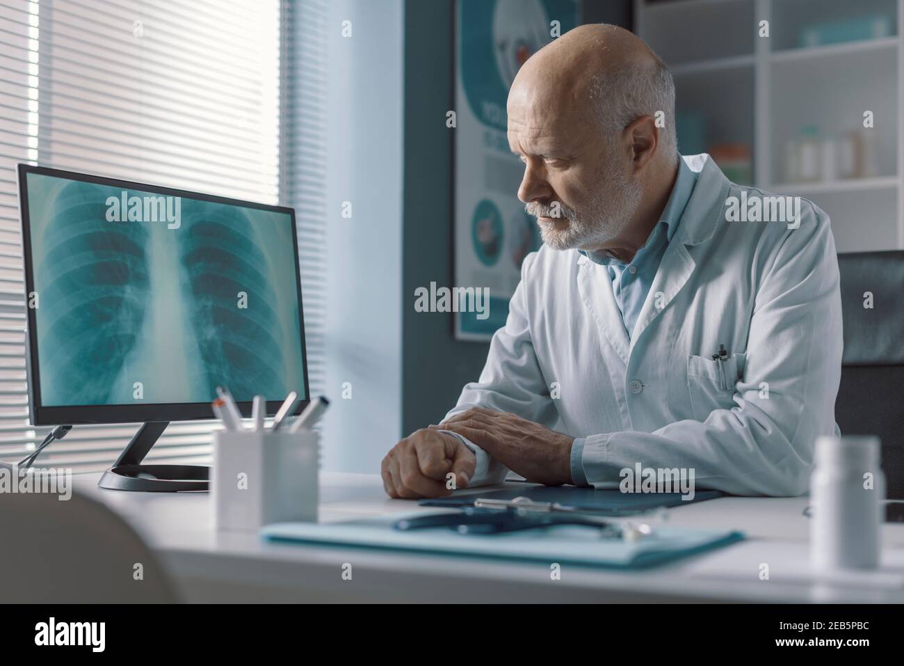 Medico professionista seduto alla scrivania dell'ufficio e che analizza un radiografia immagine sullo schermo del computer Foto Stock