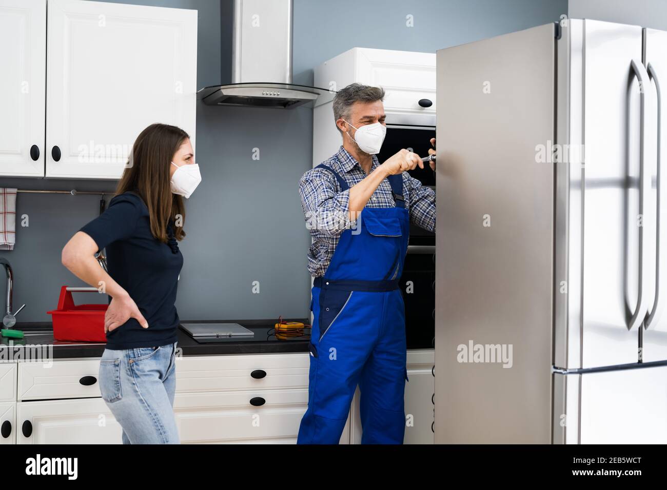 Servizio di riparazione frigorifero. Tecnico addetto alla riparazione dei  frigoriferi in maschera facciale Foto stock - Alamy