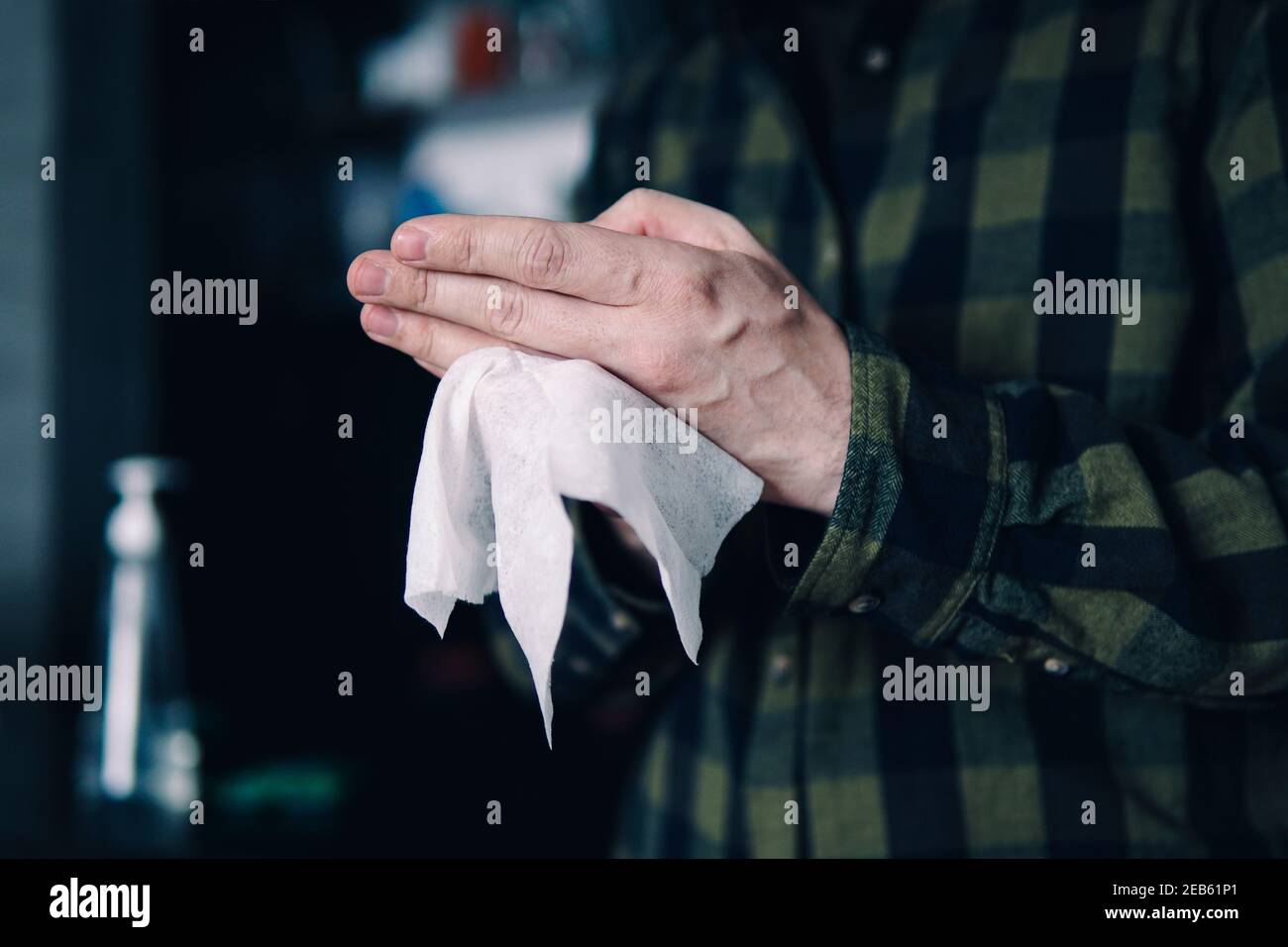 uomo che le pulisce le mani con carta bianca morbida. Disinfezione delle mani durante la pandemia del coronavirus. Pulire le mani di batteri e germi. Foto Stock